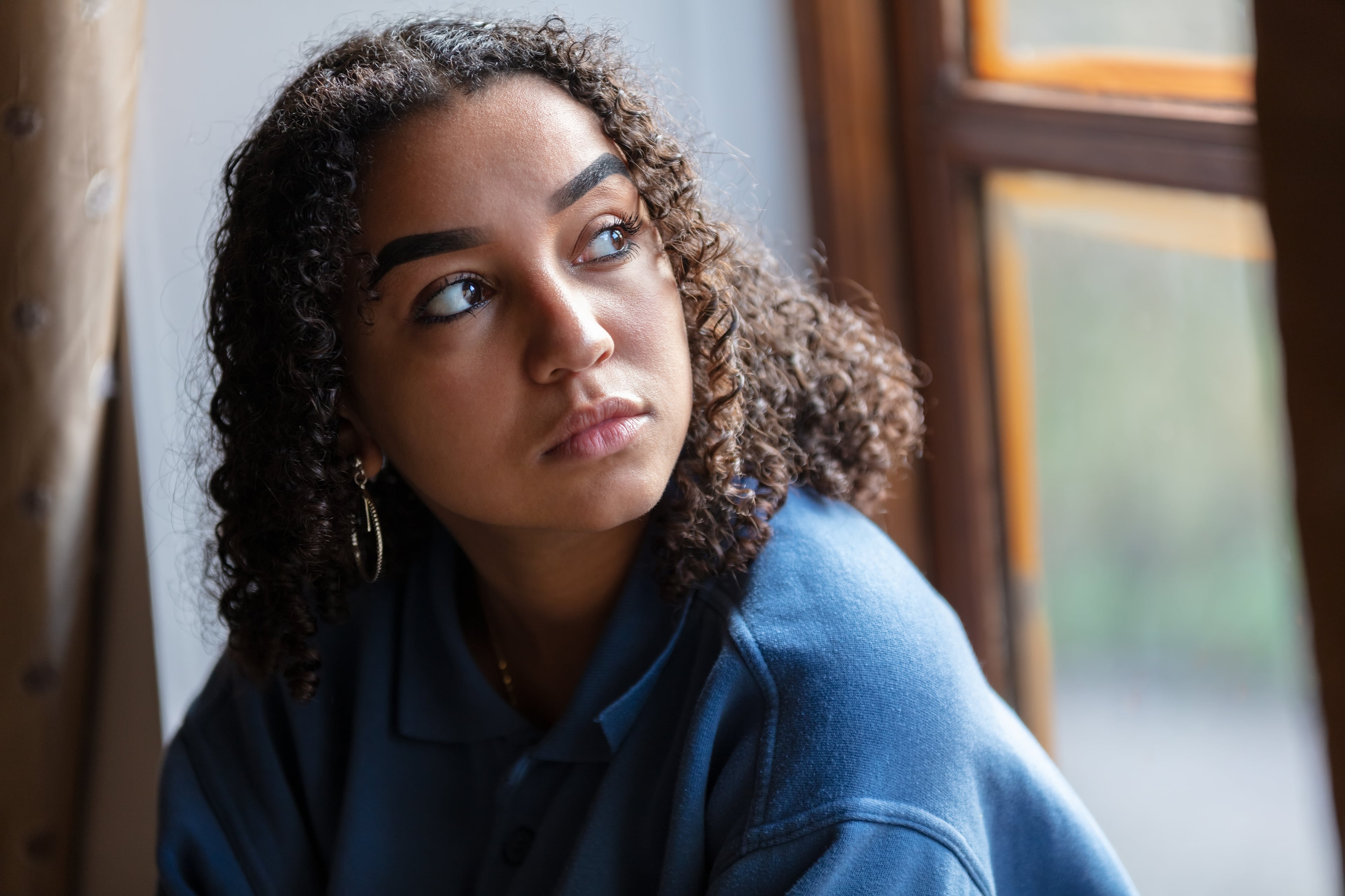 Young adult with curly hair looking up and to the right.